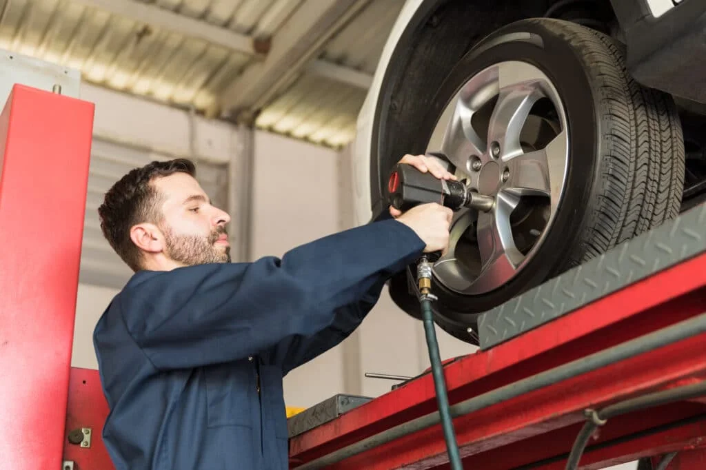Mechanic using impact gun and socket on a car wheel