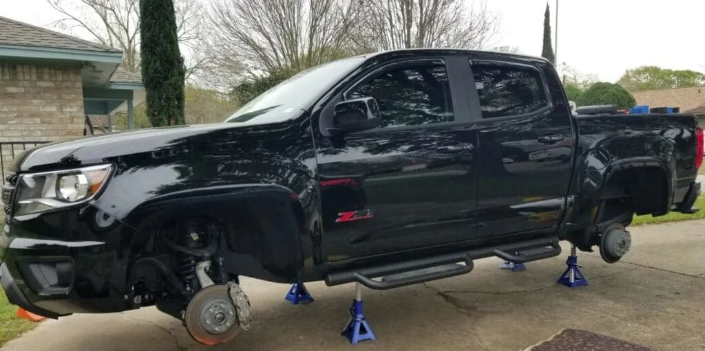A heavy pick up truck suspended on 4 adjustable jack stands
