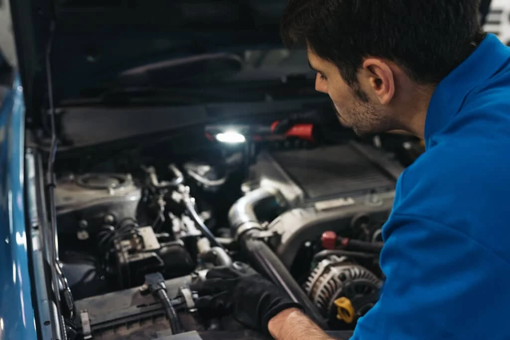 Mechanic using cordless work light to inspect Subaru engine