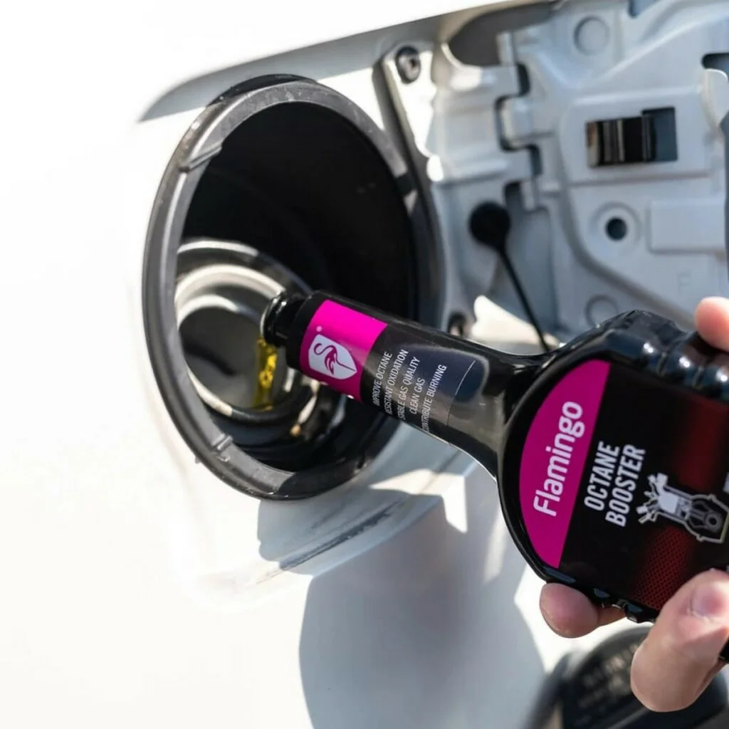 Pouring Flamingo octane booster into a gas tank