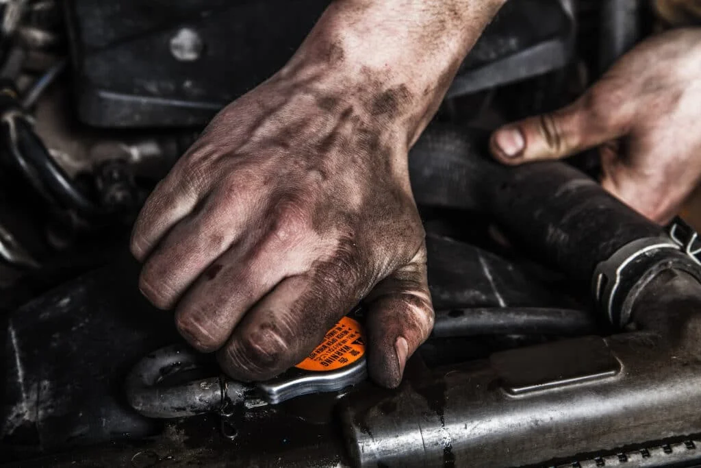 Mechanic opening oil cap with greasy hands