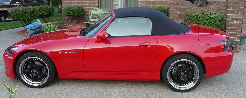 Side view of a red Honda s2000 on stock ride height with aftermarket wheels