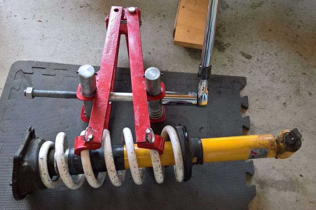 A clamshell strut spring compressor in action