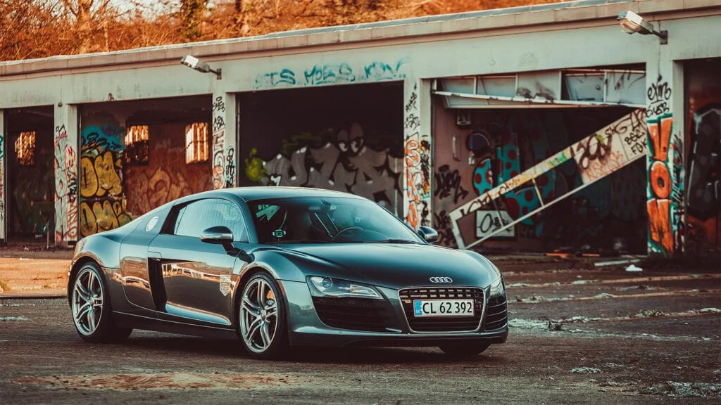 Audi R8 parked next an abandoned graffiti covered storage unit