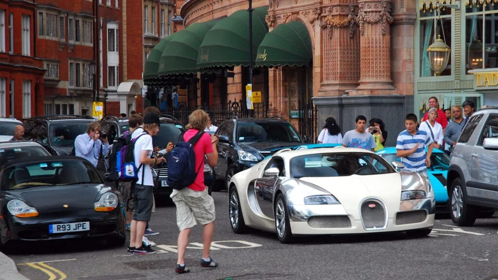 Carspotters taking pictures of a beige and chrome Bugatti Veyron