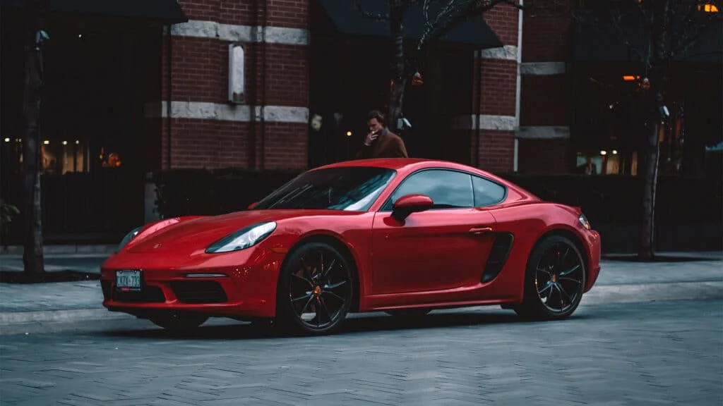 Red Porsche 718 Cayman parked on a cobbled street