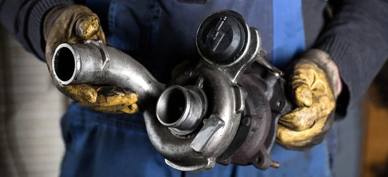 Mechanic holding a dirty turbocharger