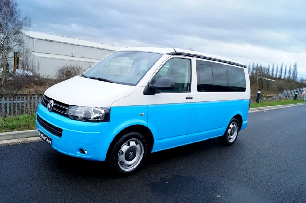 A blue and white VW van with dark window tint