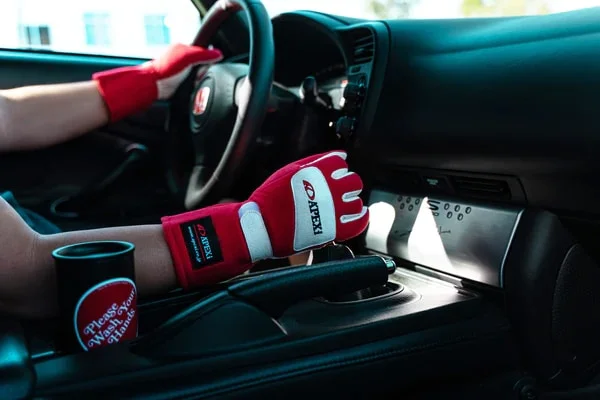 Shifting gears with red and white Apexi gloves on
