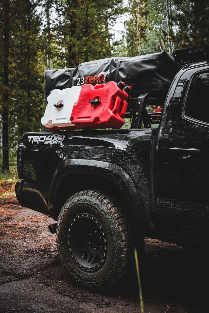 Black TRD 4x4 Tacoma with aftermarket rims and tires in a forest