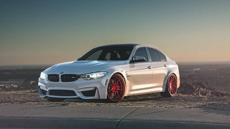 White BMW sedan with tinted windows and red rims