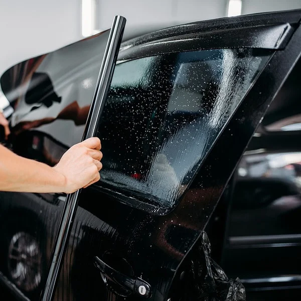 Window tint application on a black sedan