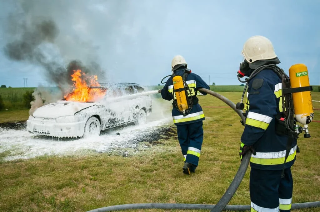 Professionals putting out a car fire using foam extinguishers