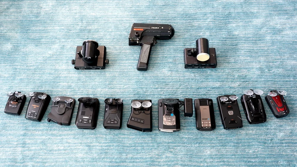 Different types of radar detectors laid out on a teal rug