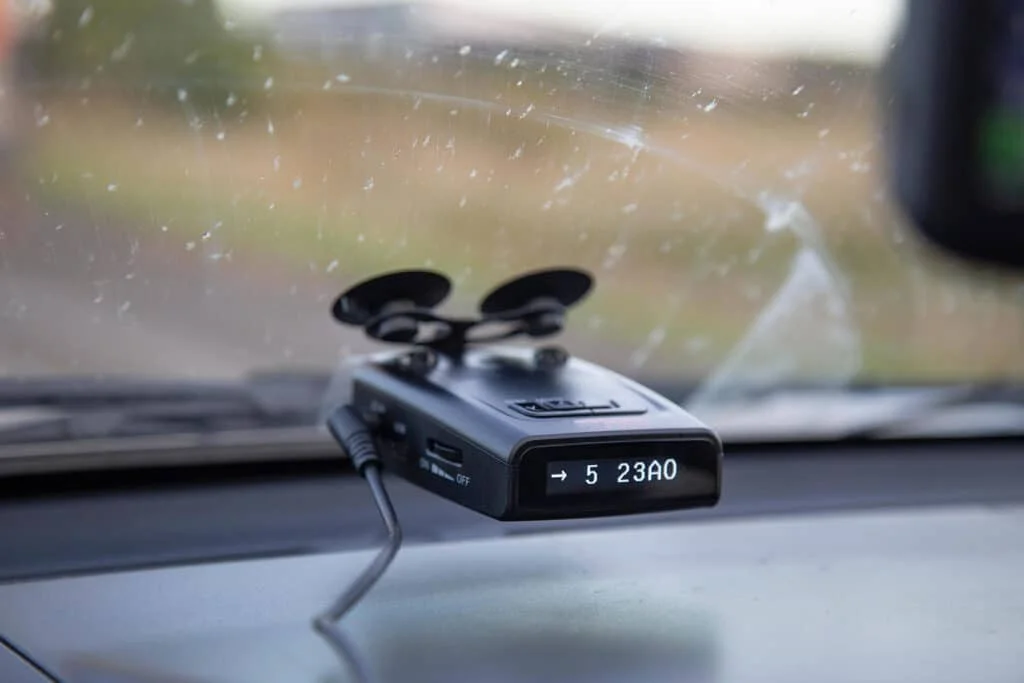 Black radar detector mounted on the windshield of a car