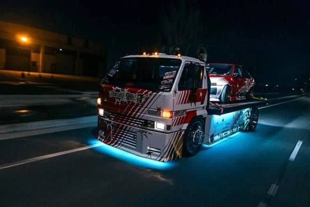 Neon-decked Dekotora truck hauling a Hachiroku AE86