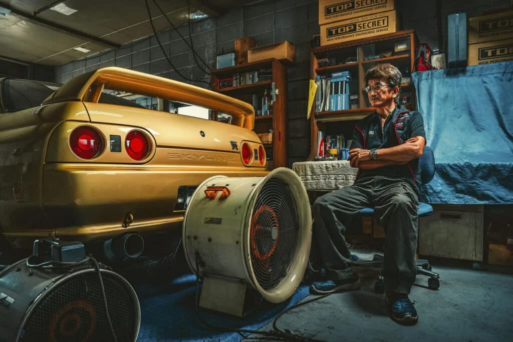 Smokey Nagata in his garage next to a gold R32 Skyline