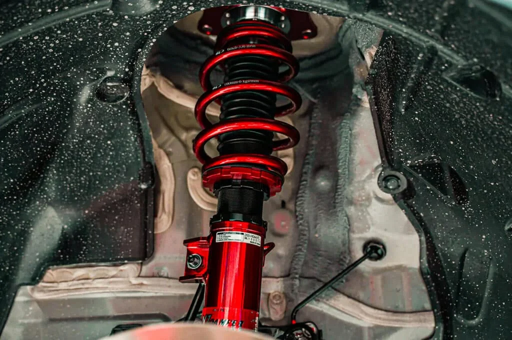 Shiny crimson red coilovers in a wheel well