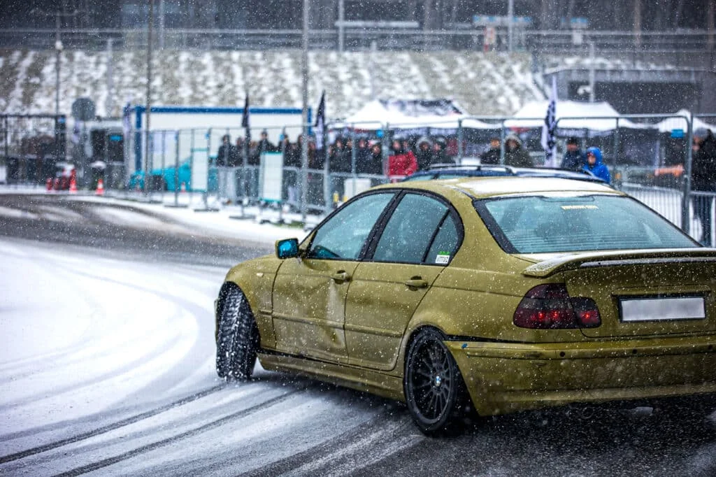 BMW with low-profile tires drifting on a snowy road