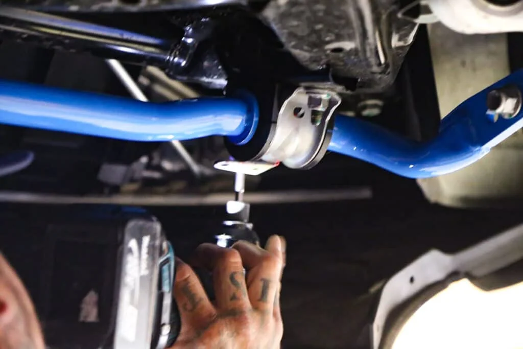 Technician installing a blue sway bar