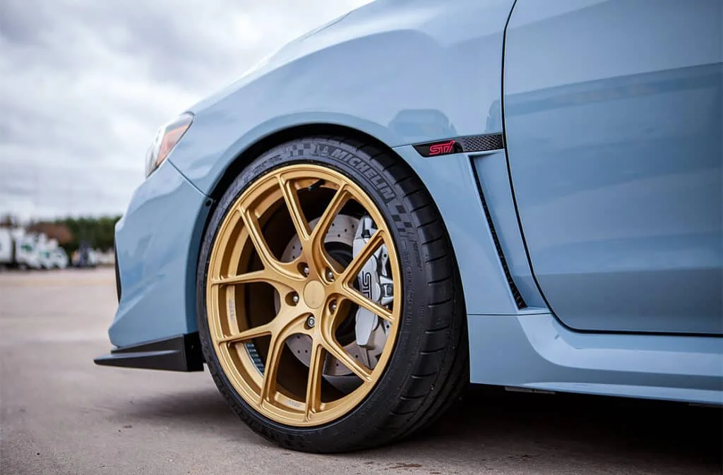 Gold Titan7 rims on a cool gray khaki WRX