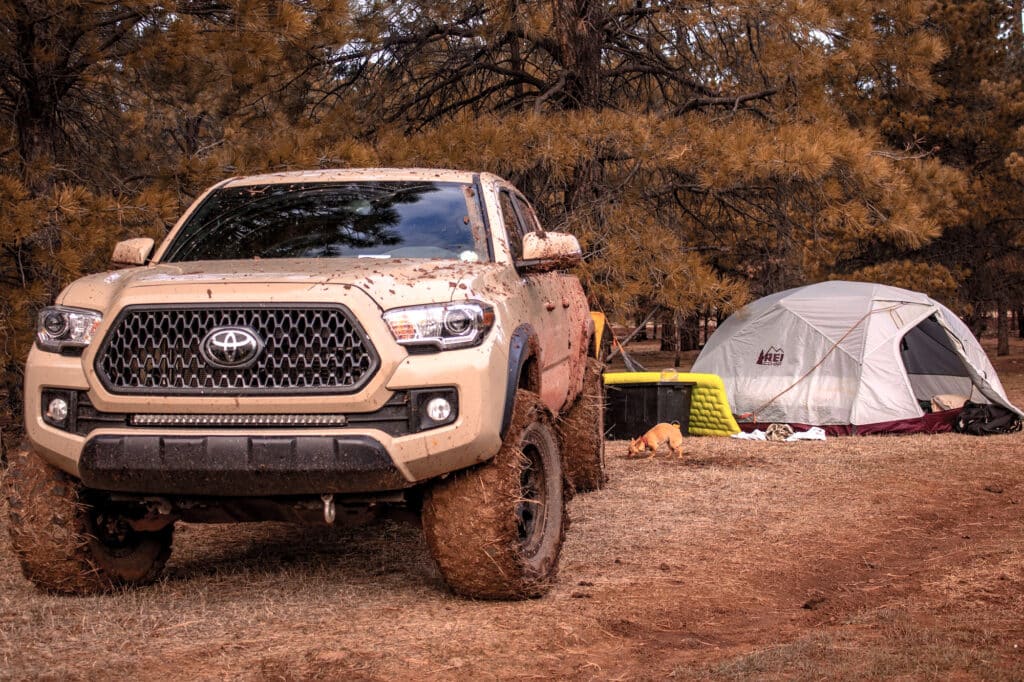 Muddy gen 3 tacoma next to a campsite